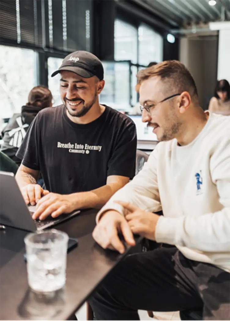 Two men sitting in a cafe working on a laptop